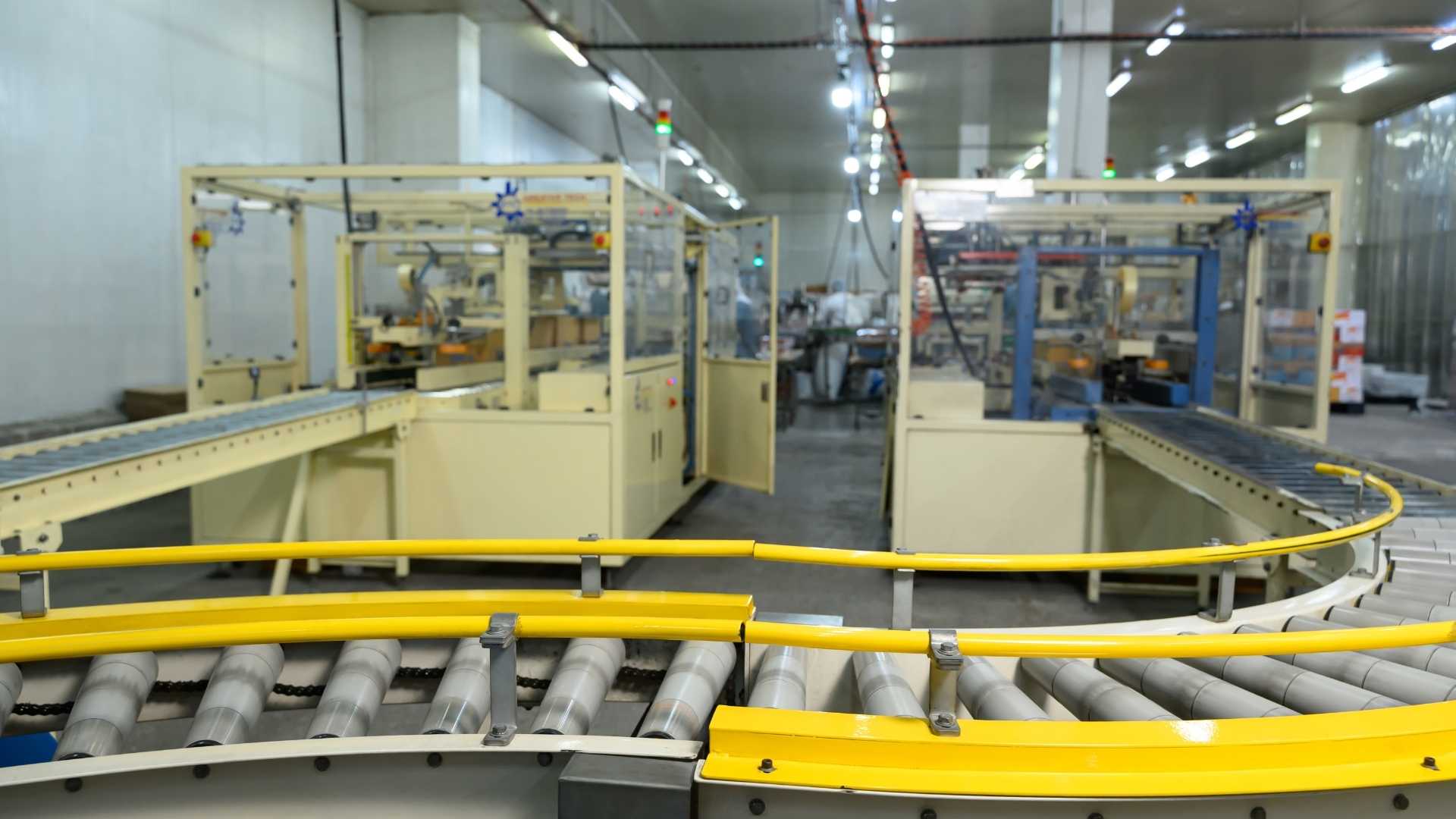 Ingeniero evaluando maquinaria de envasado automatizado en una fábrica moderna para mejorar la eficiencia operativa y la producción.